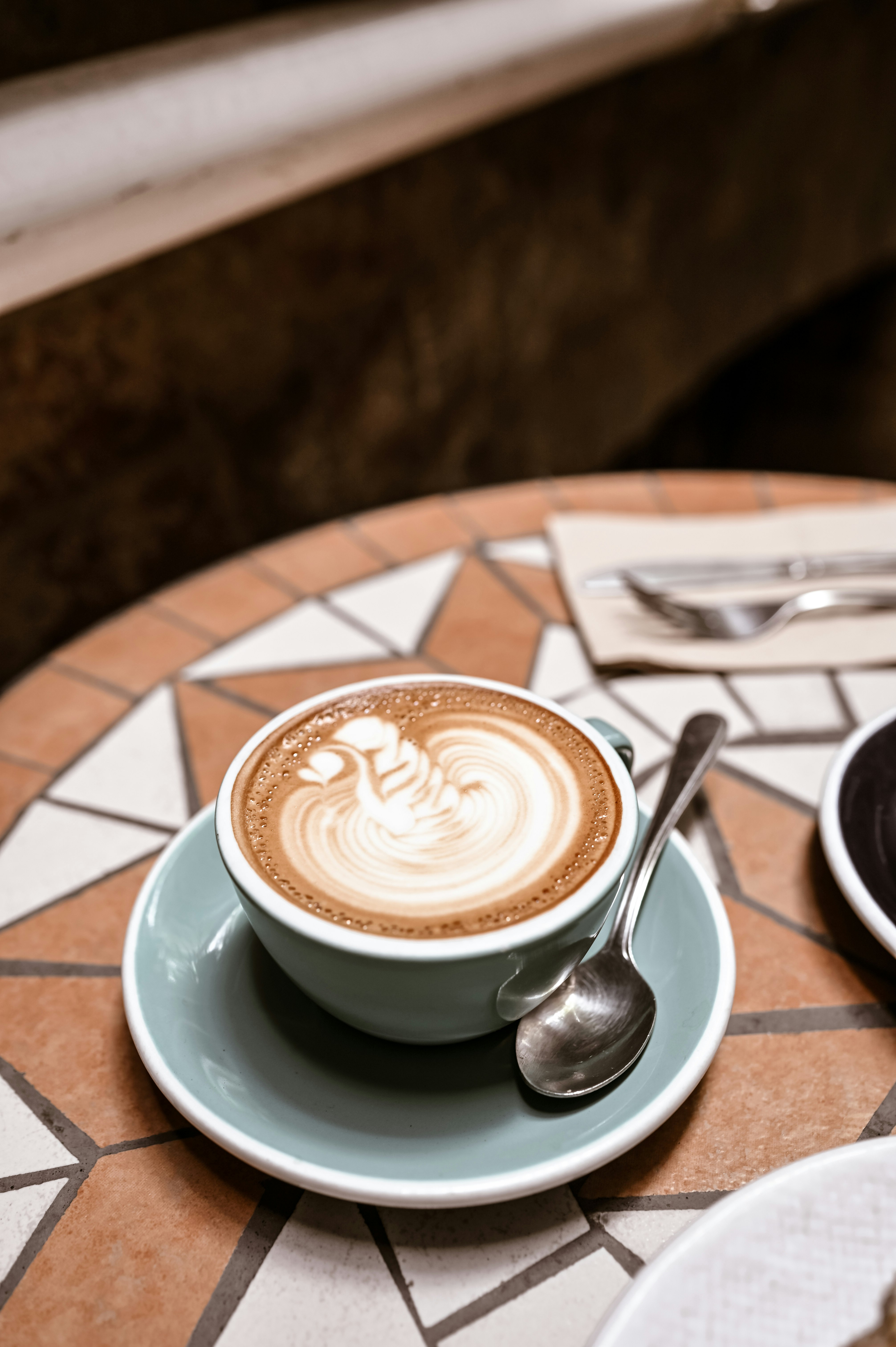 white ceramic cup with saucer and stainless steel spoon